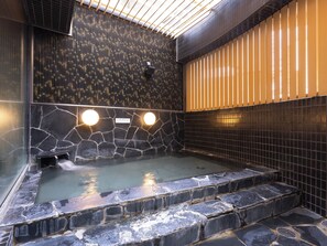 A hot tub with stone walls and a tiled floor, surrounded by a wooden fence and a metal railing. - APA Hotel Sendai Eki Itsutsubashi (Sendai)