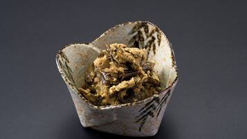 A ceramic bowl with a rustic design containing a food dish.