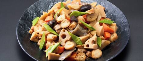 A dish with various vegetables and tofu on a dark plate.