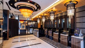 Un hall d’hôtel moderne avec un comptoir d’accueil, des guichets d’enregistrement et un lustre.