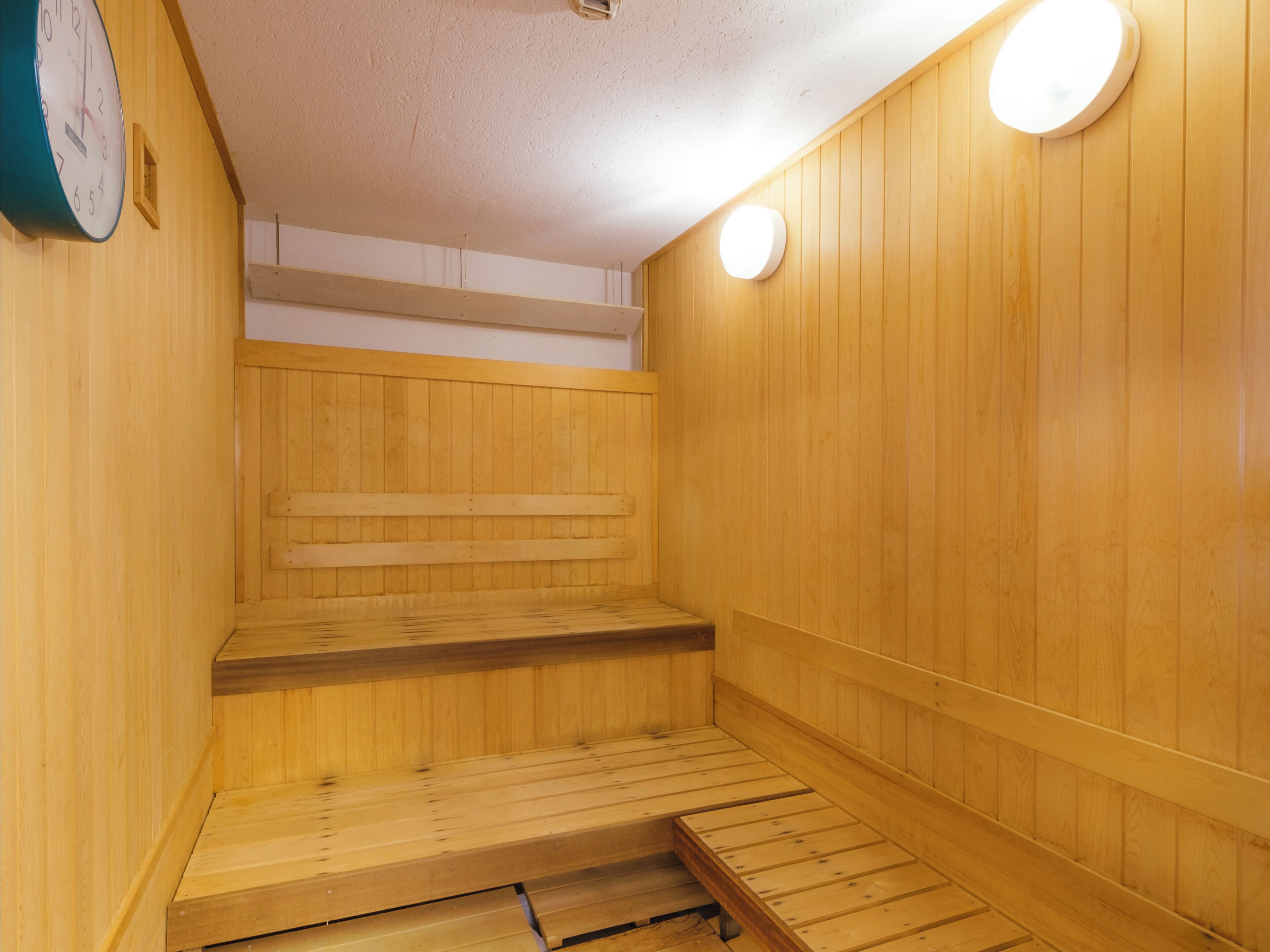 A sauna with wooden benches and a clock on the wall.