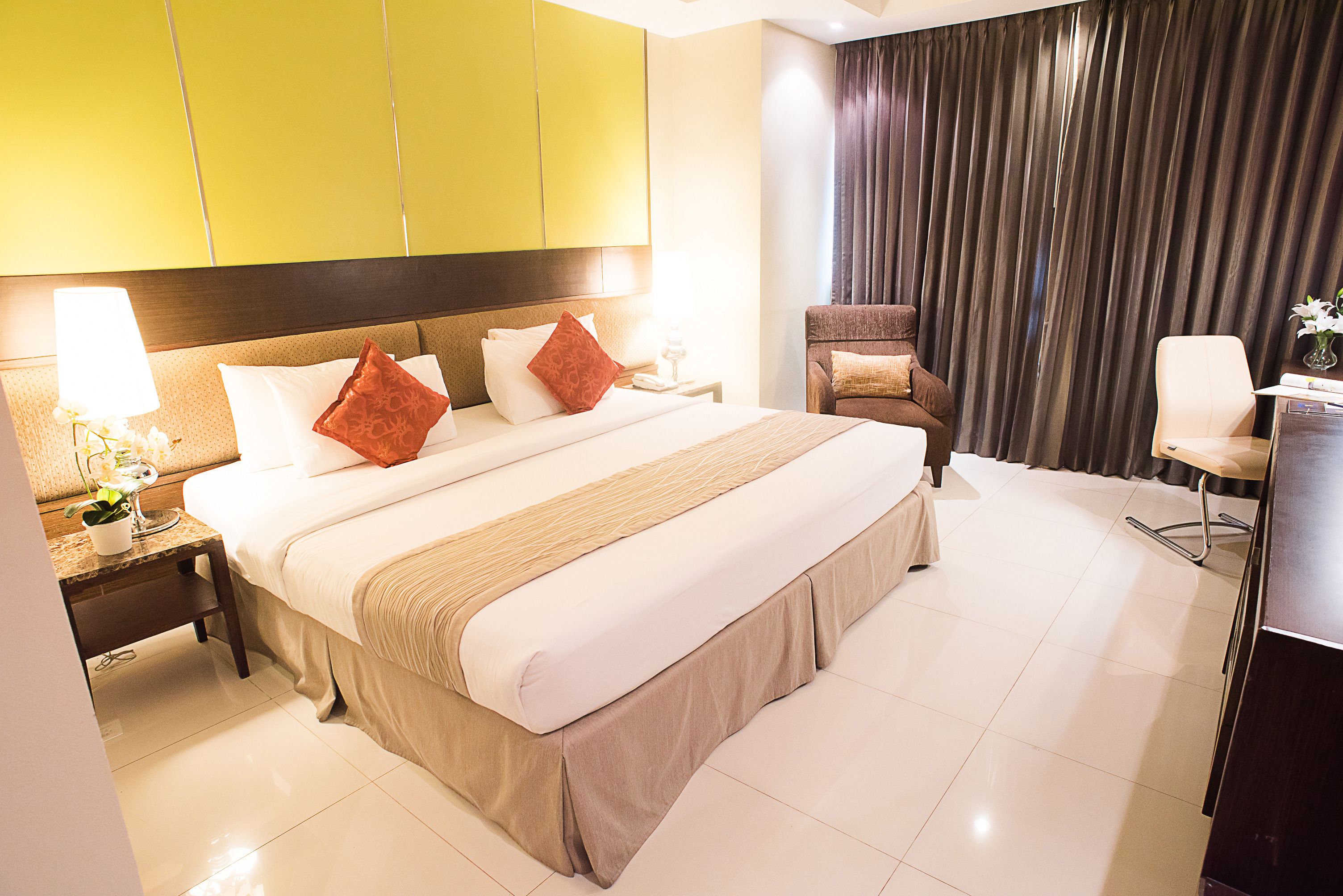 Ein Hotelzimmer mit einem großen Bett, einem Sessel, einem Schreibtisch und einem Vorhang.