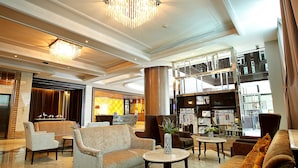 A spacious lobby with a high ceiling, a grand chandelier, and a seating area with sofas and armchairs. - Intimate Hotel Pattaya (Pattaya)