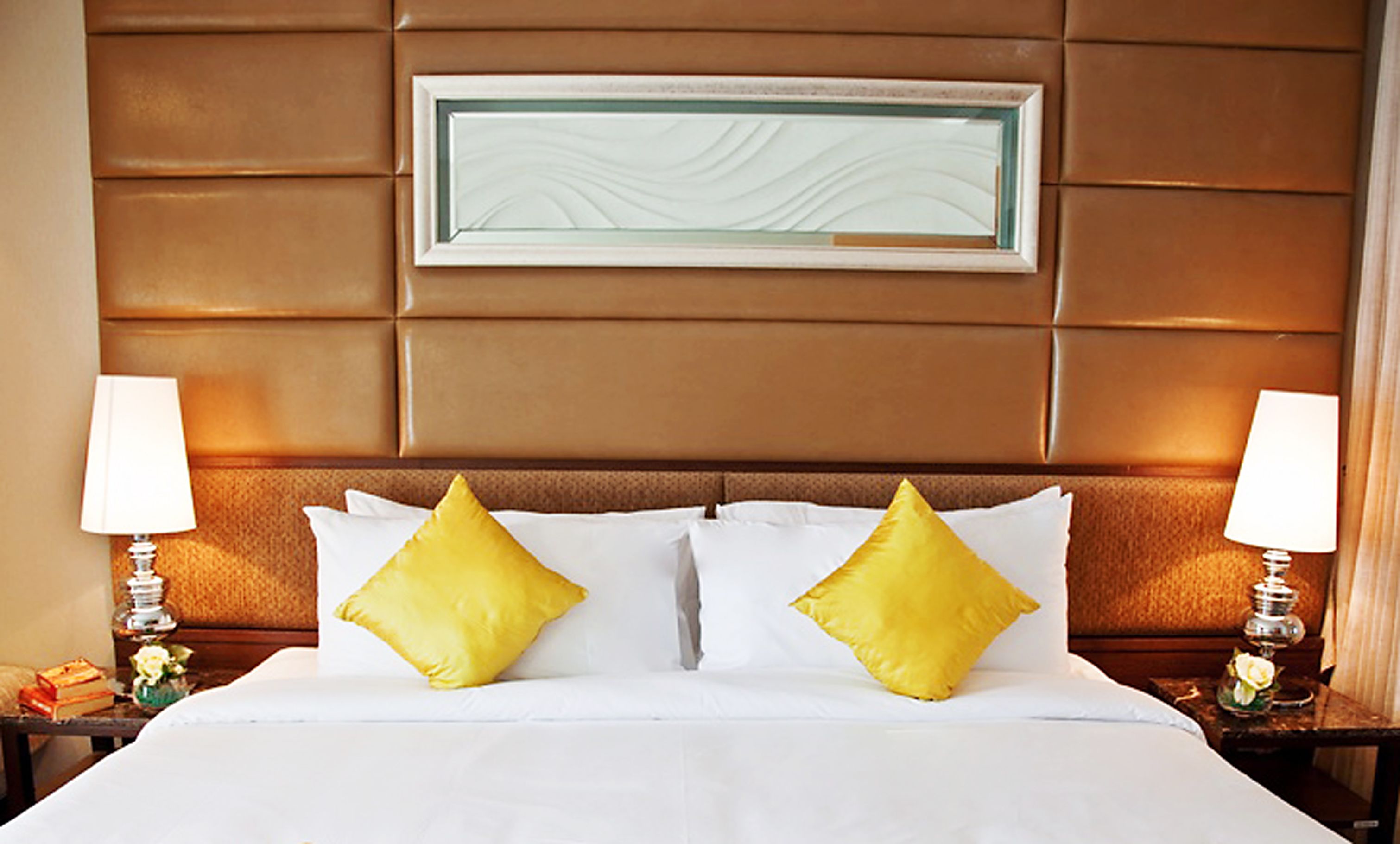 Una habitació d'hotel amb un llit gran, dues làmpades laterals i una obra d'art emmarcada a la paret.