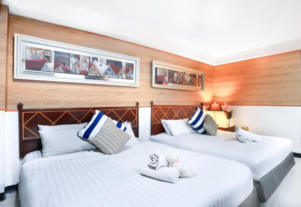 A hotel room with two beds, wooden headboards, and framed pictures on the wall.