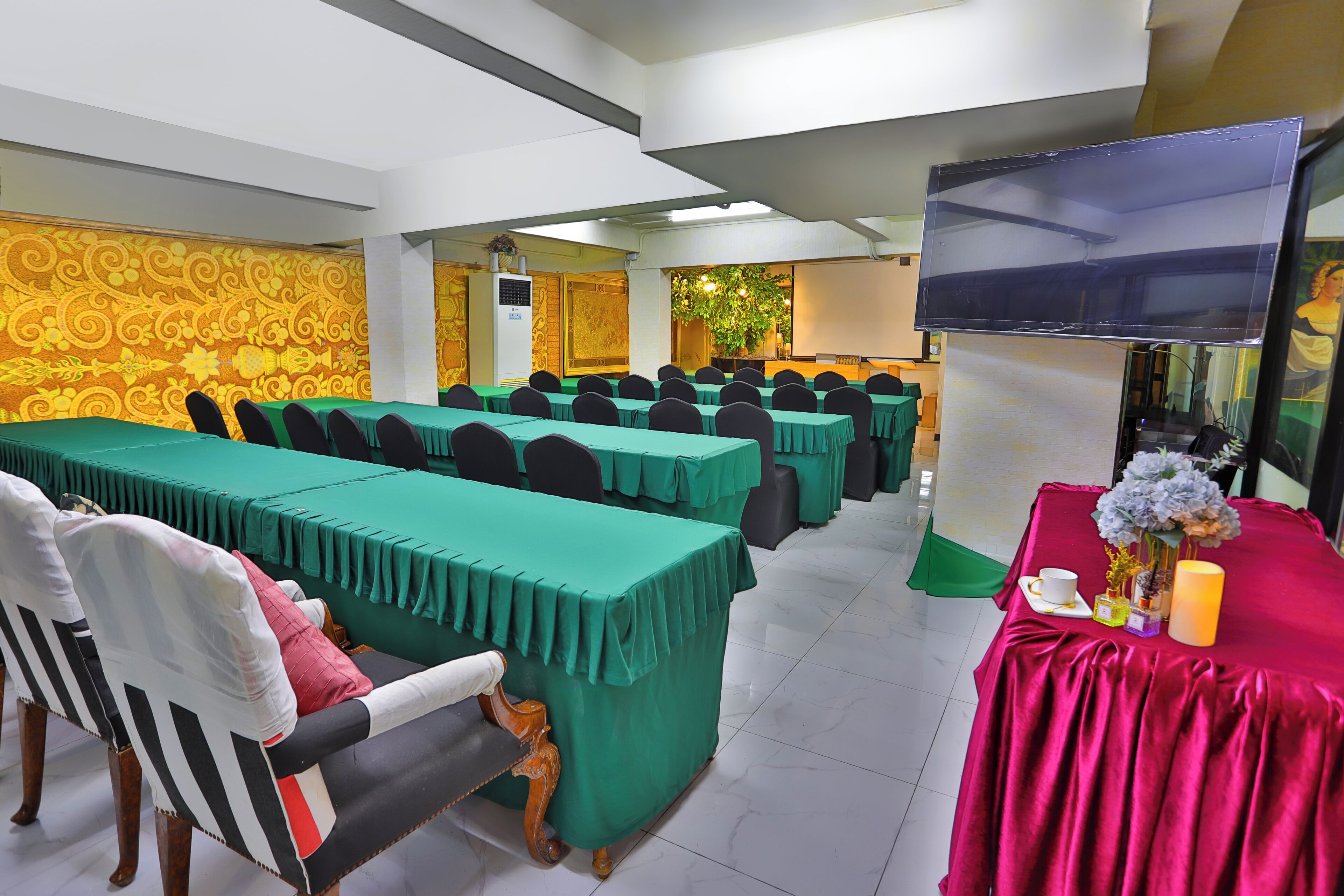 A conference room with multiple tables, chairs, a television, and a decorative plant.