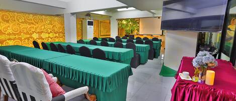 A conference room with multiple tables, chairs, a television, and a decorative plant.