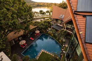 Ein Swimmingpool mit Liegestühlen, umgeben von Grünflächen mit Blick auf ein Gewässer.