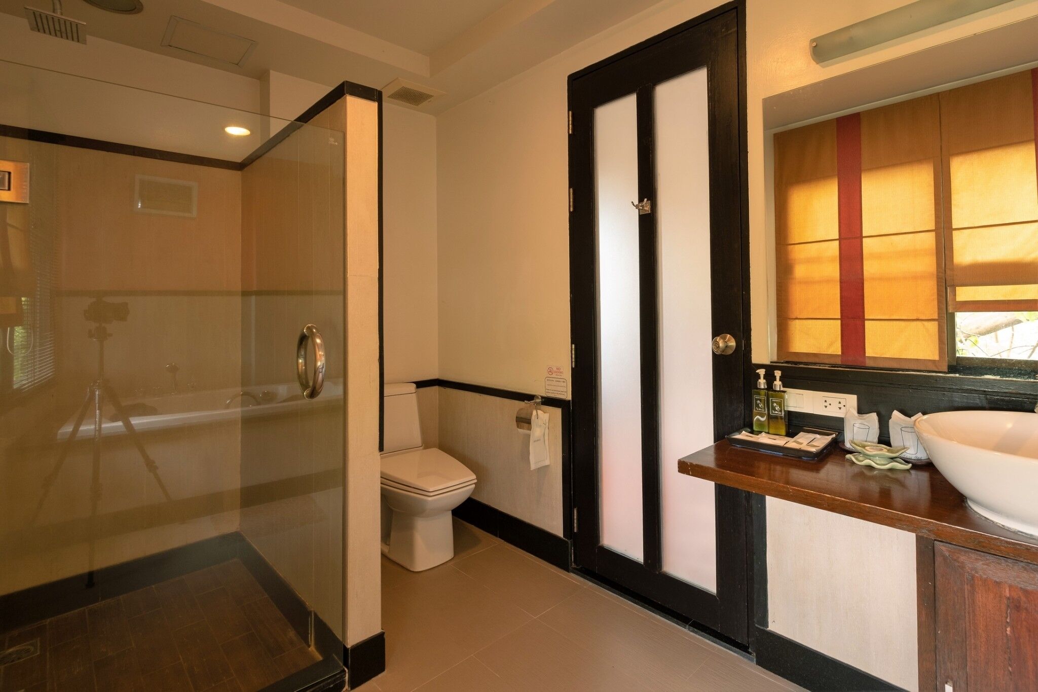 A modern bathroom with a glass-enclosed shower, a toilet, and a vanity with a large mirror and sink.