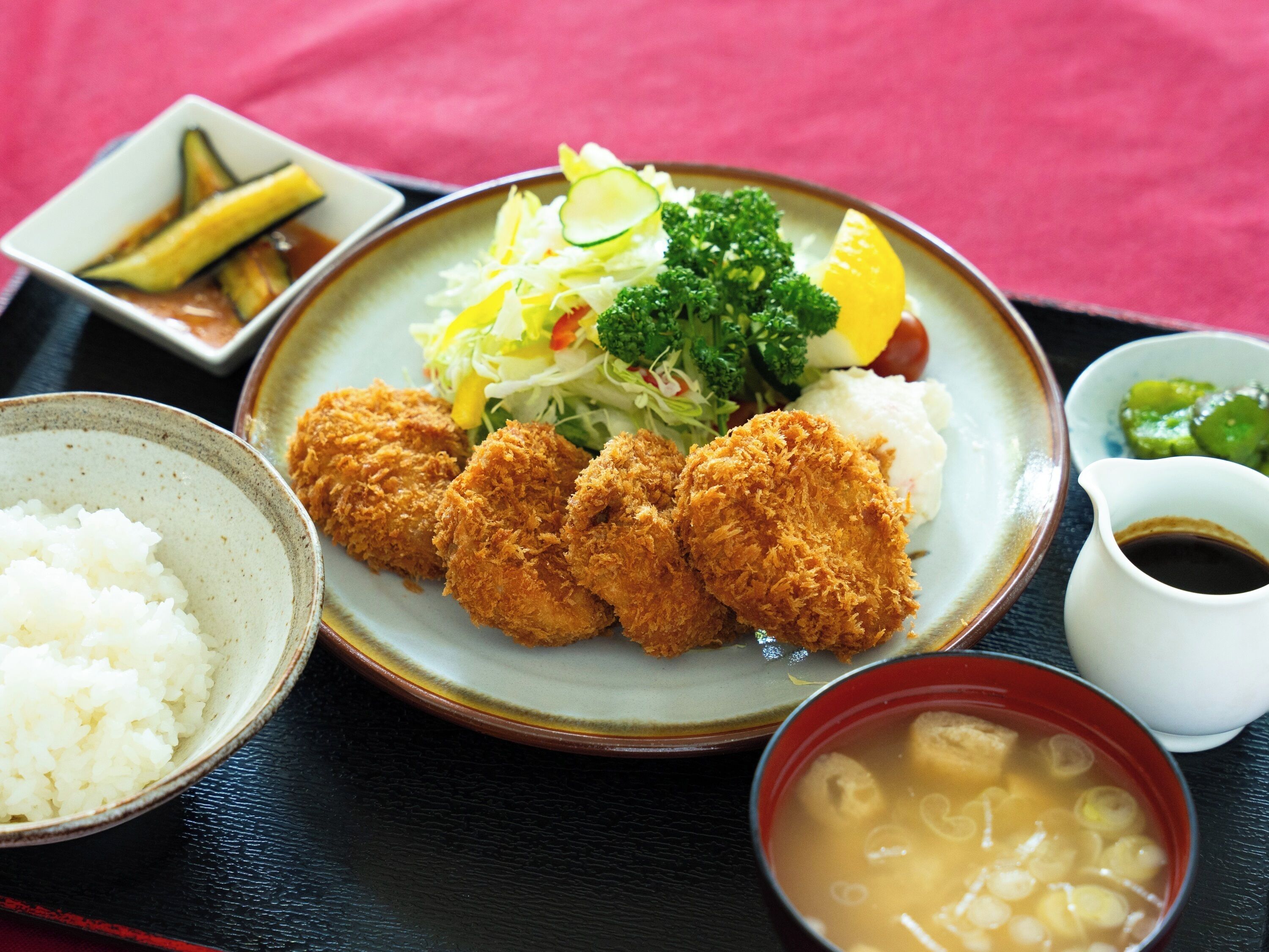 A plate of food including fried items, rice, and a bowl of soup.