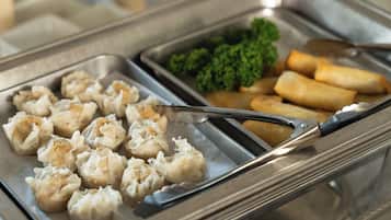 A buffet with dumplings, broccoli, and spring rolls.