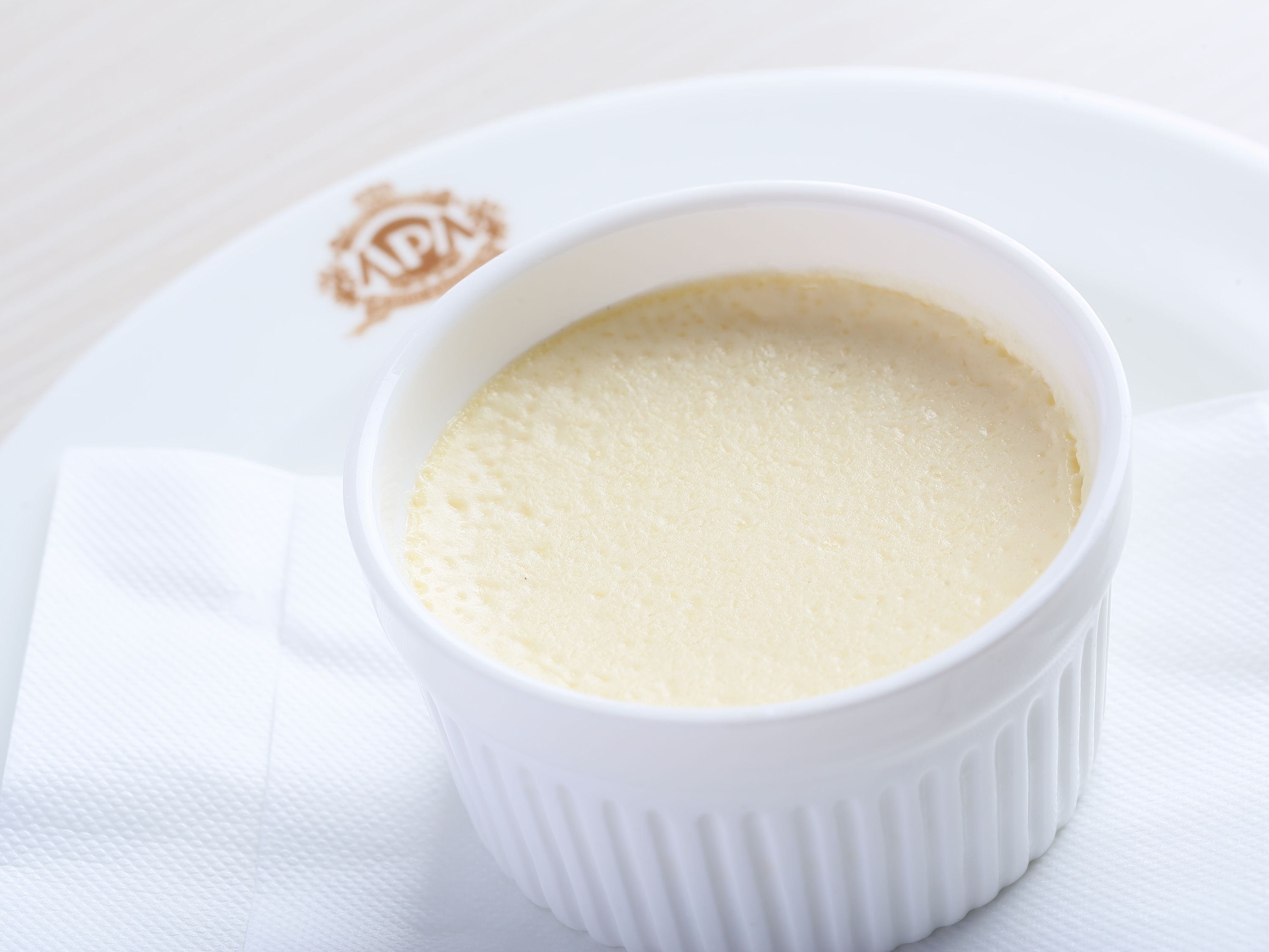 A white ramekin on a white plate with a logo.