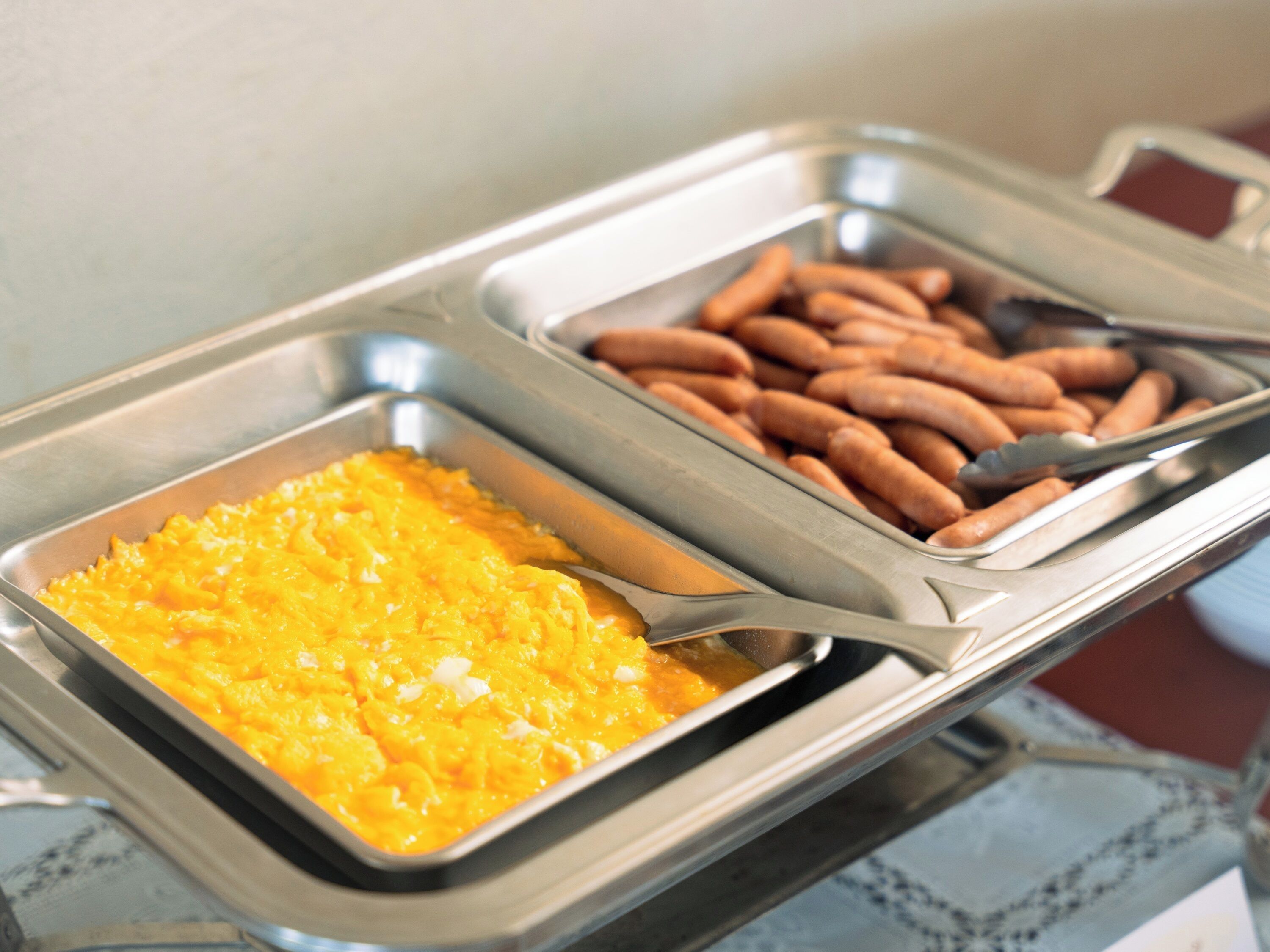 Ein Buffetschild mit Rührei, Würstchen und einer Portion Mac and Cheese.