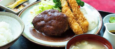 A plate of food including tempura shrimp, a meatball, and vegetables.