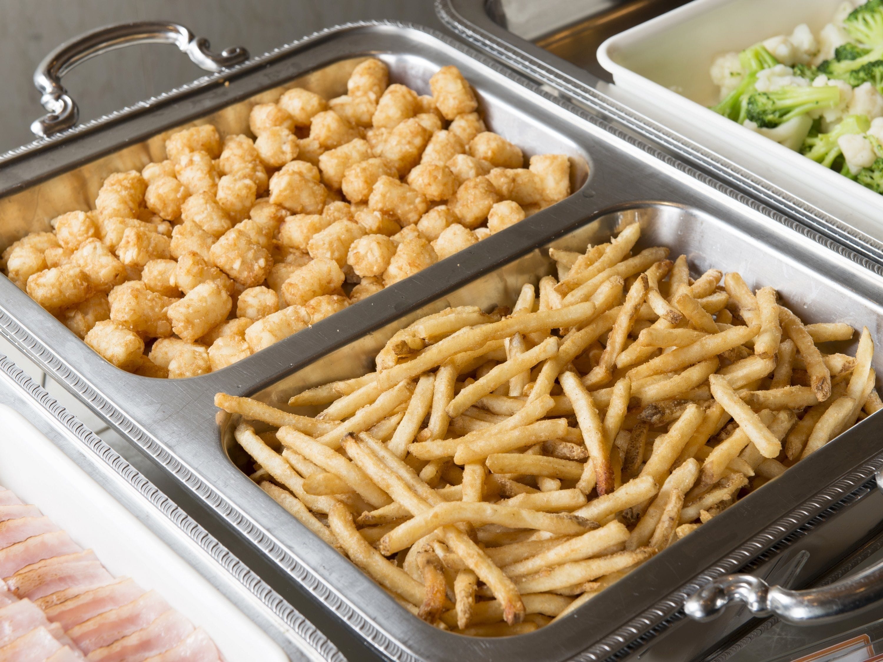 Un bufé con papas fritas, croquetas de papa y brócoli.