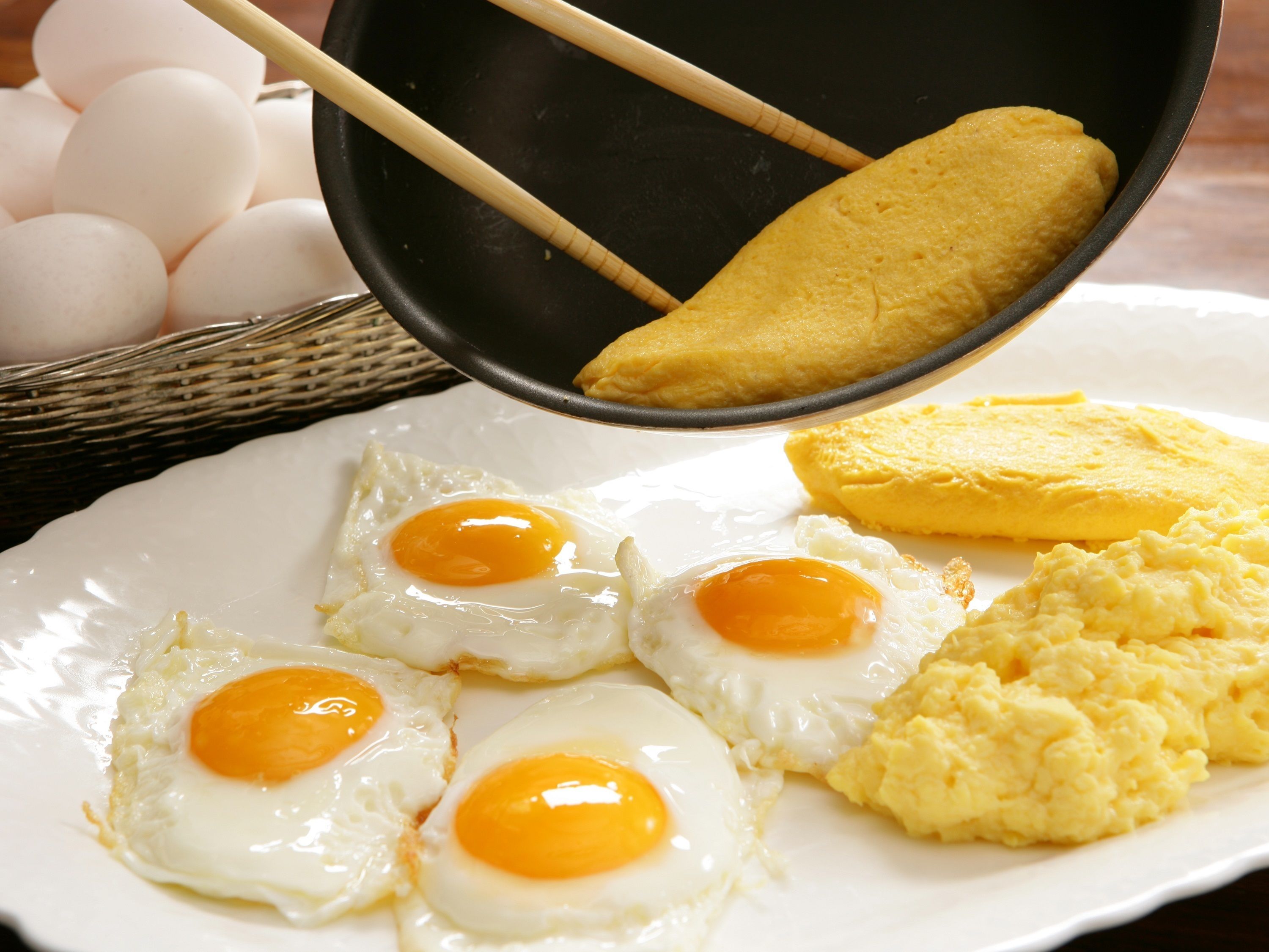 A plate with four sunny-side-up eggs, a piece of omelette, and scrambled eggs.
