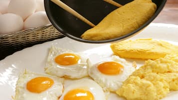 A plate with four sunny-side-up eggs, a piece of omelette, and scrambled eggs.