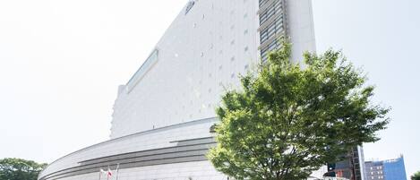 A modern hotel with a curved facade, multiple floors, and a prominent entrance.