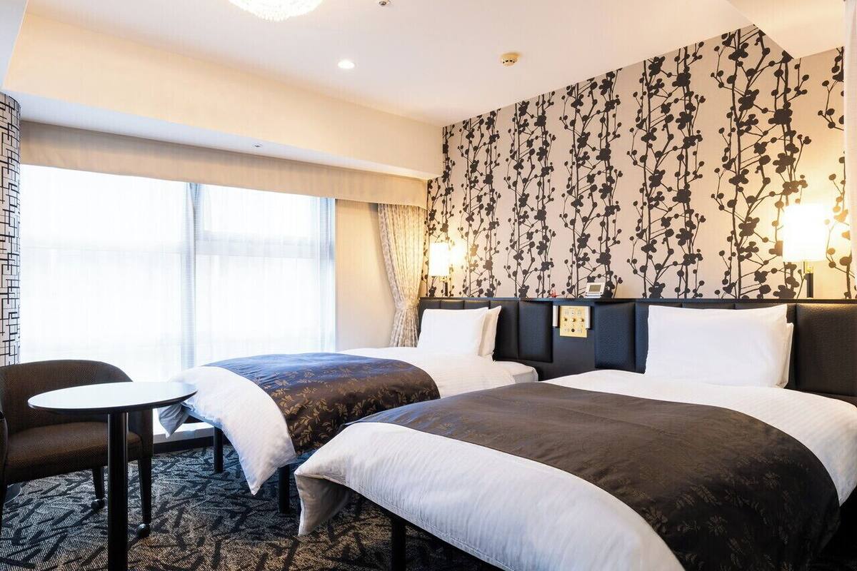 Een hotelkamer met twee bedden, een tafeltje en een stoel.
