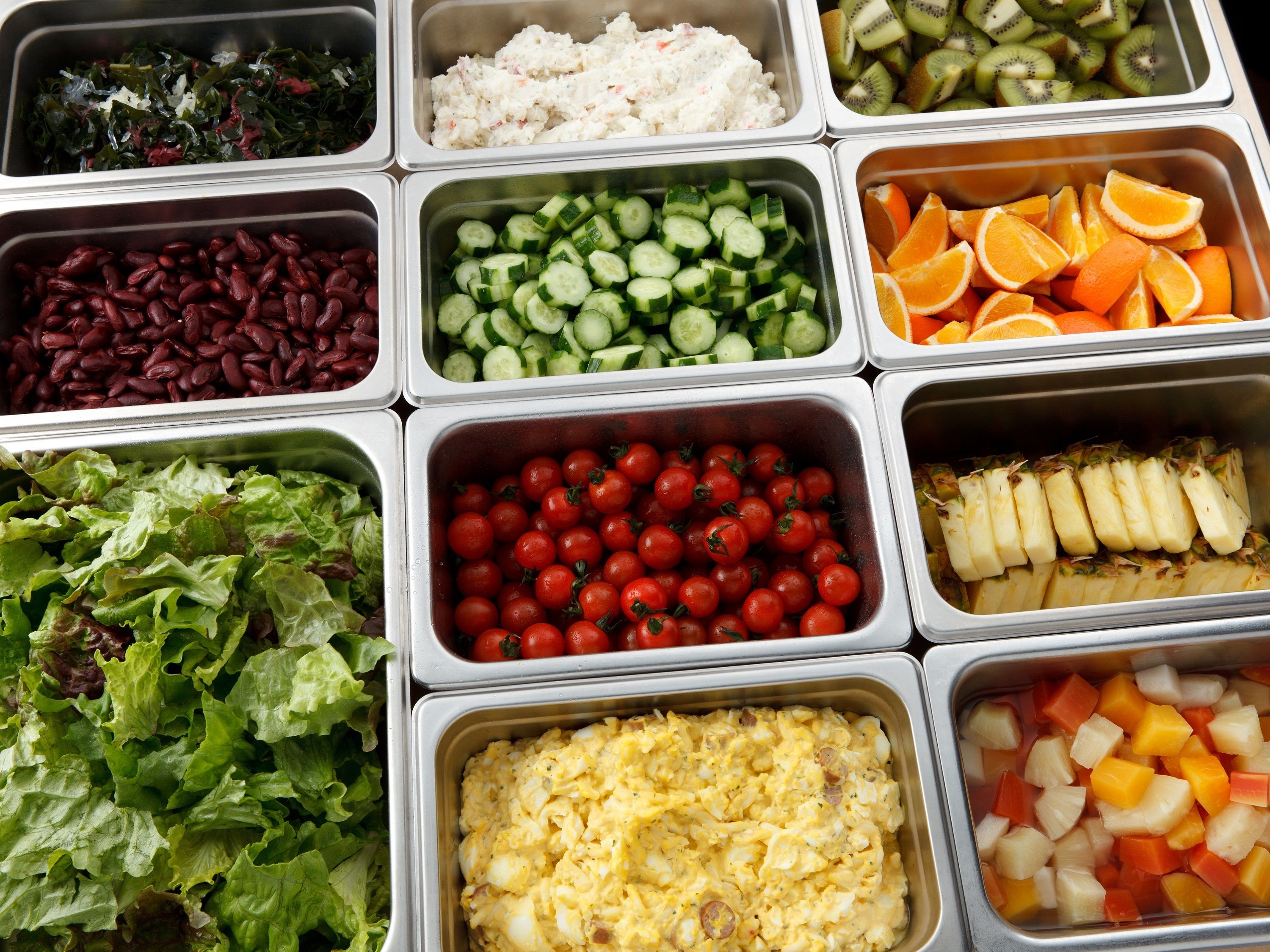 A buffet with various food options including salads, fruits, and vegetables.