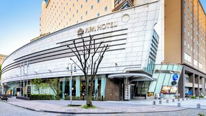 Un hôtel moderne à la façade incurvée, doté de grandes fenêtres et d’une entrée imposante.