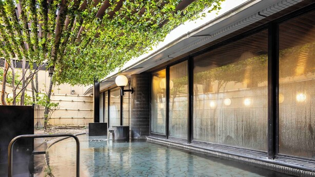 Une piscine sur le toit, dotée d’un sol carrelé, entourée de grandes fenêtres et agrémentée d’une pergola couverte de verdure.