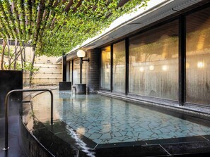 Ein Pool auf dem Dach mit gefliestem Boden, umgeben von großen Fenstern und einer Pergola mit Grünpflanzen.