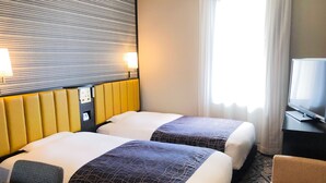 Une chambre d’hôtel avec deux lits, une télévision, un bureau et une chaise.