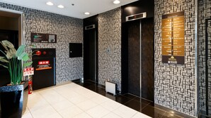 Un hall d’hôtel moderne avec un plan des étages, des ascenseurs et un panneau de commande d’alarme incendie.