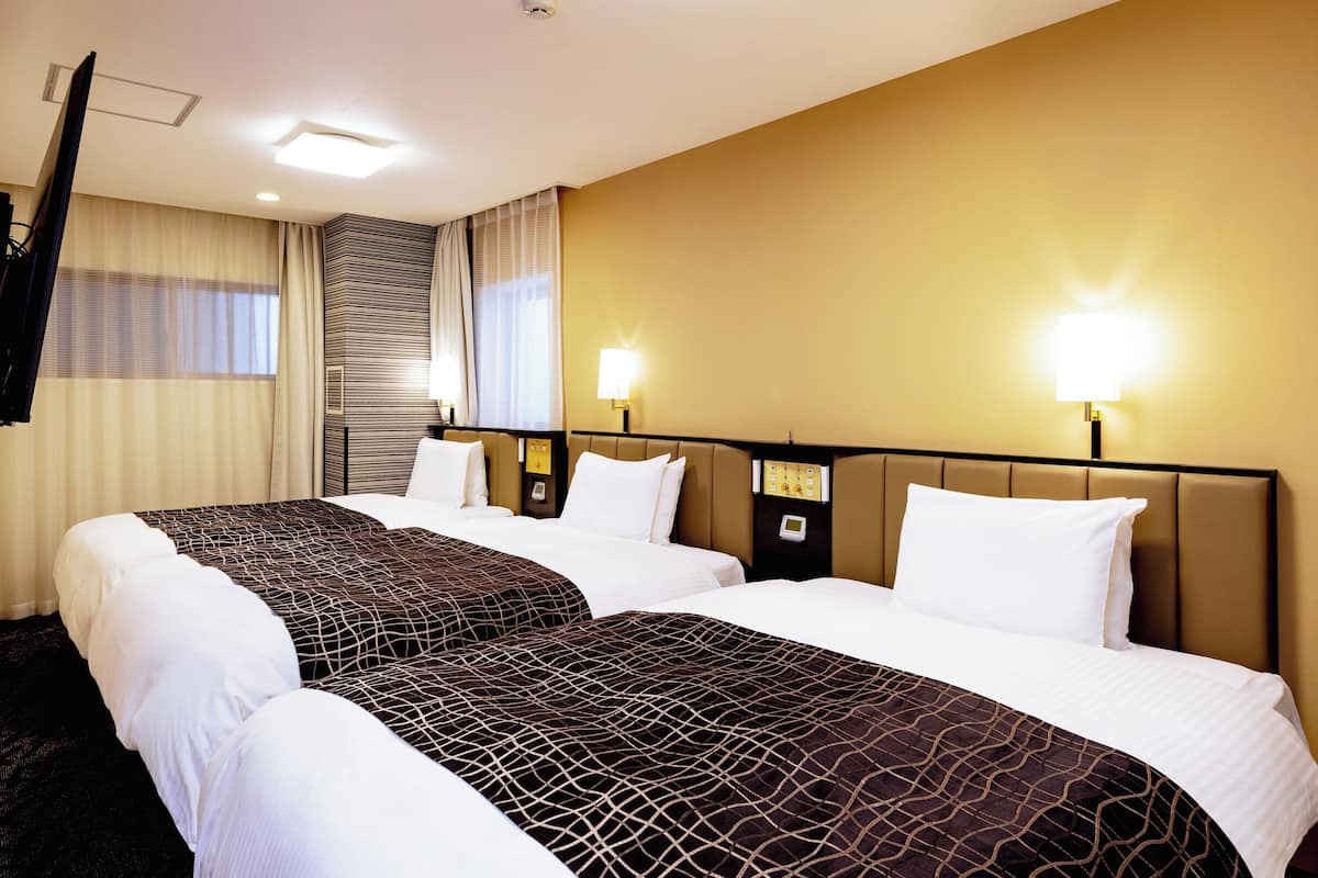 Ein Hotelzimmer mit zwei Betten, einem Flachbildfernseher und einer Minibar.