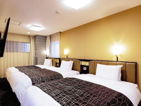 A hotel room with two beds, a flat-screen TV, and a minibar.