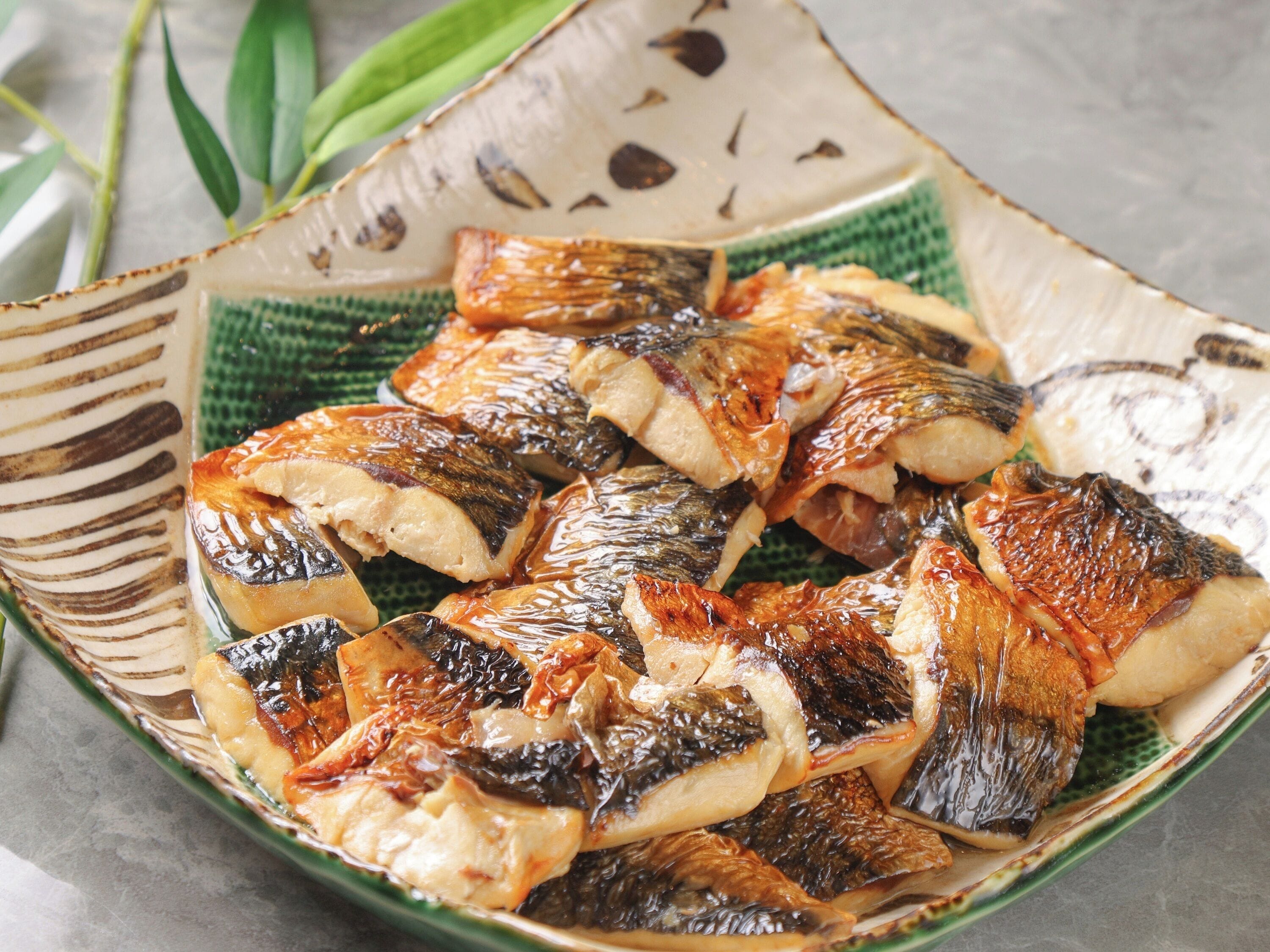 Un plat en céramique contenant du poisson grillé.