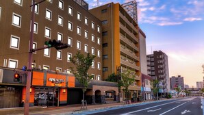 A hotel with a modern design, featuring a prominent orange sign, multiple floors, and a clear view of the street. - APA Hotel Saga Ekimae Chuo (Saga)