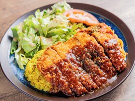 Un plato con milanesa de pollo, arroz amarillo y una ensalada.