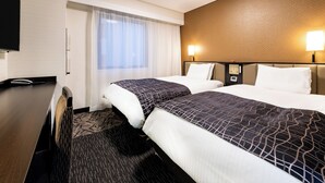 Une chambre d’hôtel avec deux lits, un bureau et une télévision.