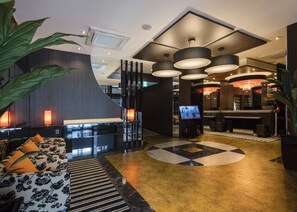 Eine moderne Hotelhalle mit Empfangsbereich, Sitzgelegenheiten und einer großen Kristallleuchtre.