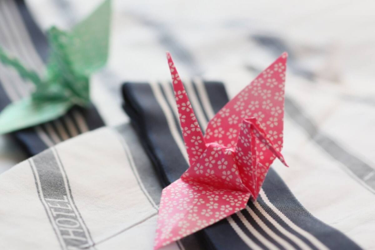Dos pájaros de origami sobre una superficie a rayas con un letrero de hotel.