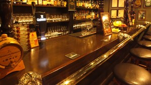 A bar with shelves of liquor bottles, a Guinness tap, and a menu board.