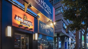 A hotel with a sign for APA HOTEL and a bar named VISH PUB.