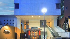 Das Hotel APA mit modernem Design, das eine markante Eingangspartei, eine Treppe und eine gut beleuchtete Fassade zeigt.