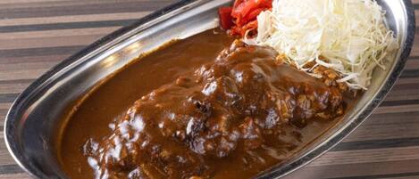 Un plato con un guiso de carne, verdura blanca desmenuzada y un pimiento rojo.