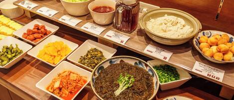 A buffet with various dishes including kimchi, pickled vegetables, and different types of noodles.