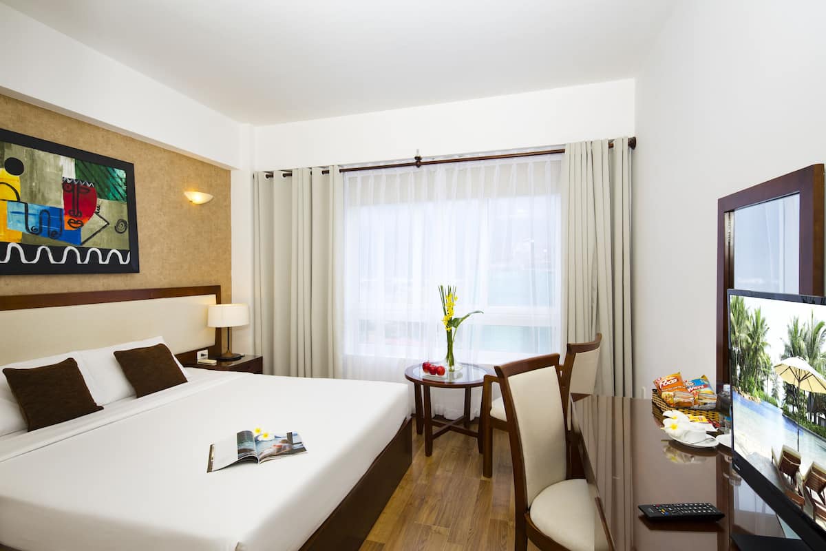 Una habitación de hotel con una cama grande, una mesita con aperitivos, un televisor y un cuadro en la pared.
