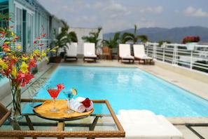 A poolside setting with a table set for two, featuring a drink, a towel, and a rose. - Sunny Hotel (Nha Trang)