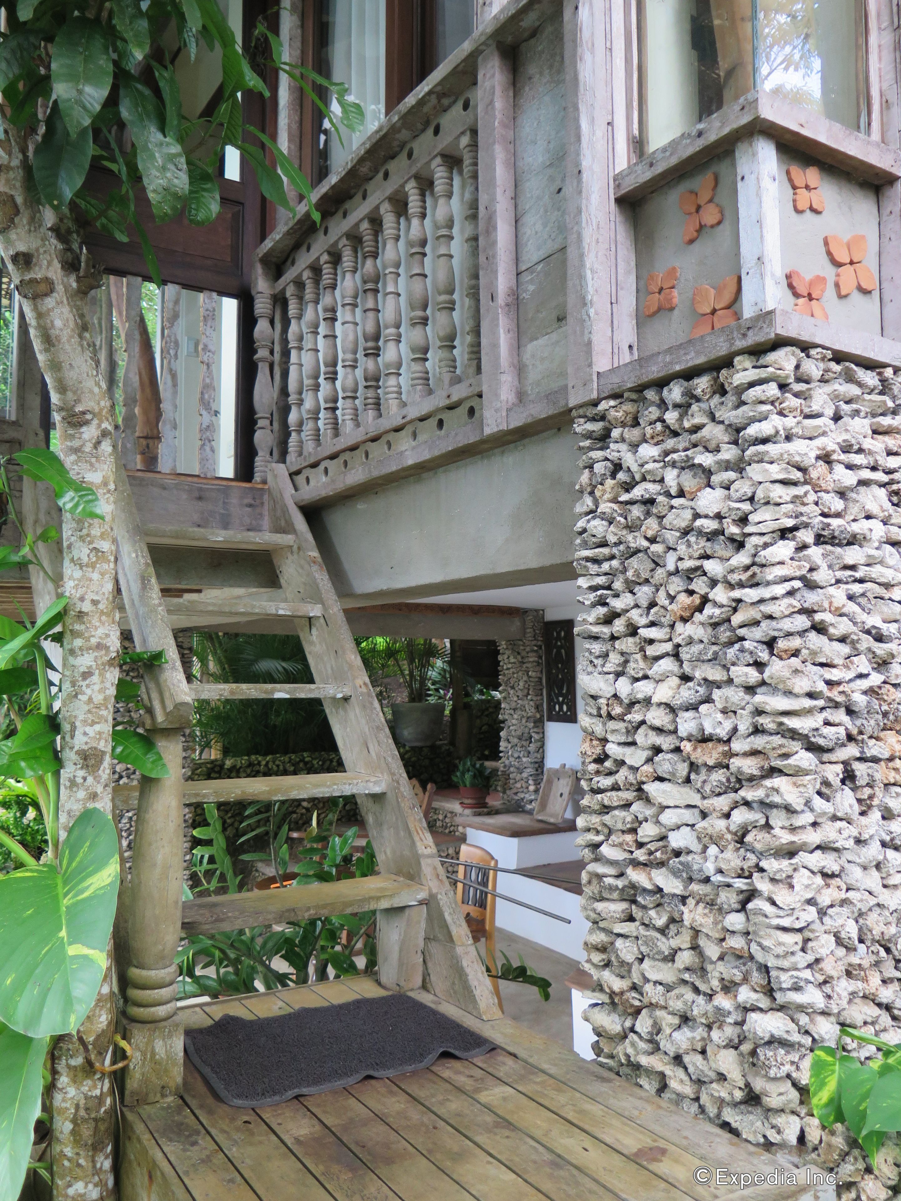 Una escalera de madera que lleva a un balcón con un muro de piedra.