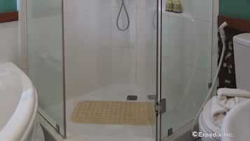 Een douche met glazen wanden, een handdouche, een glazen deur en een witte betegelde muur.