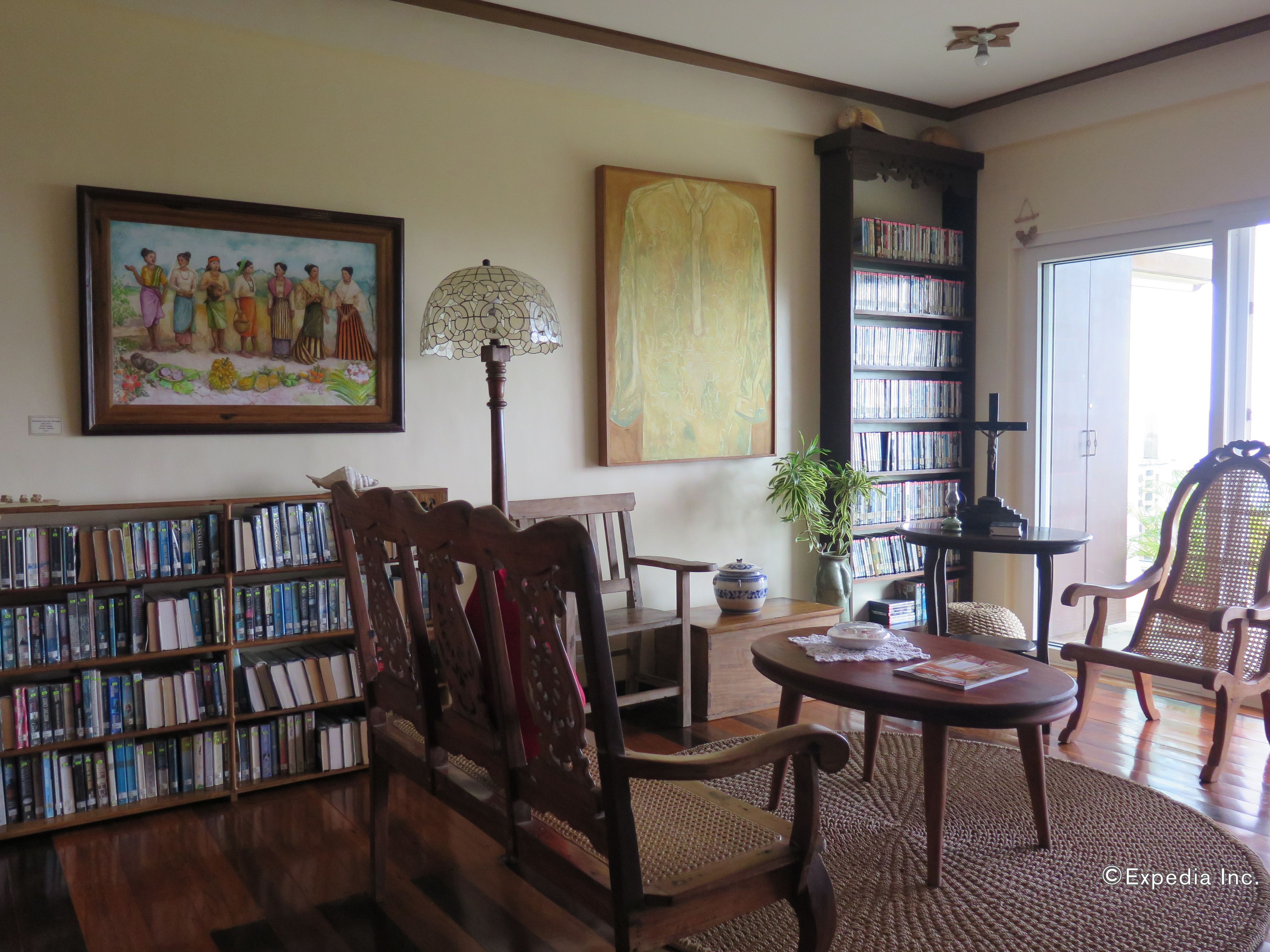 A library with wooden bookshelves, a round table, and chairs.
