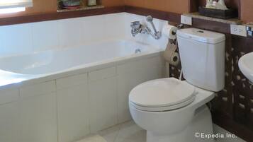 Een badkamer met een bad, toilet en planken met toiletartikelen.