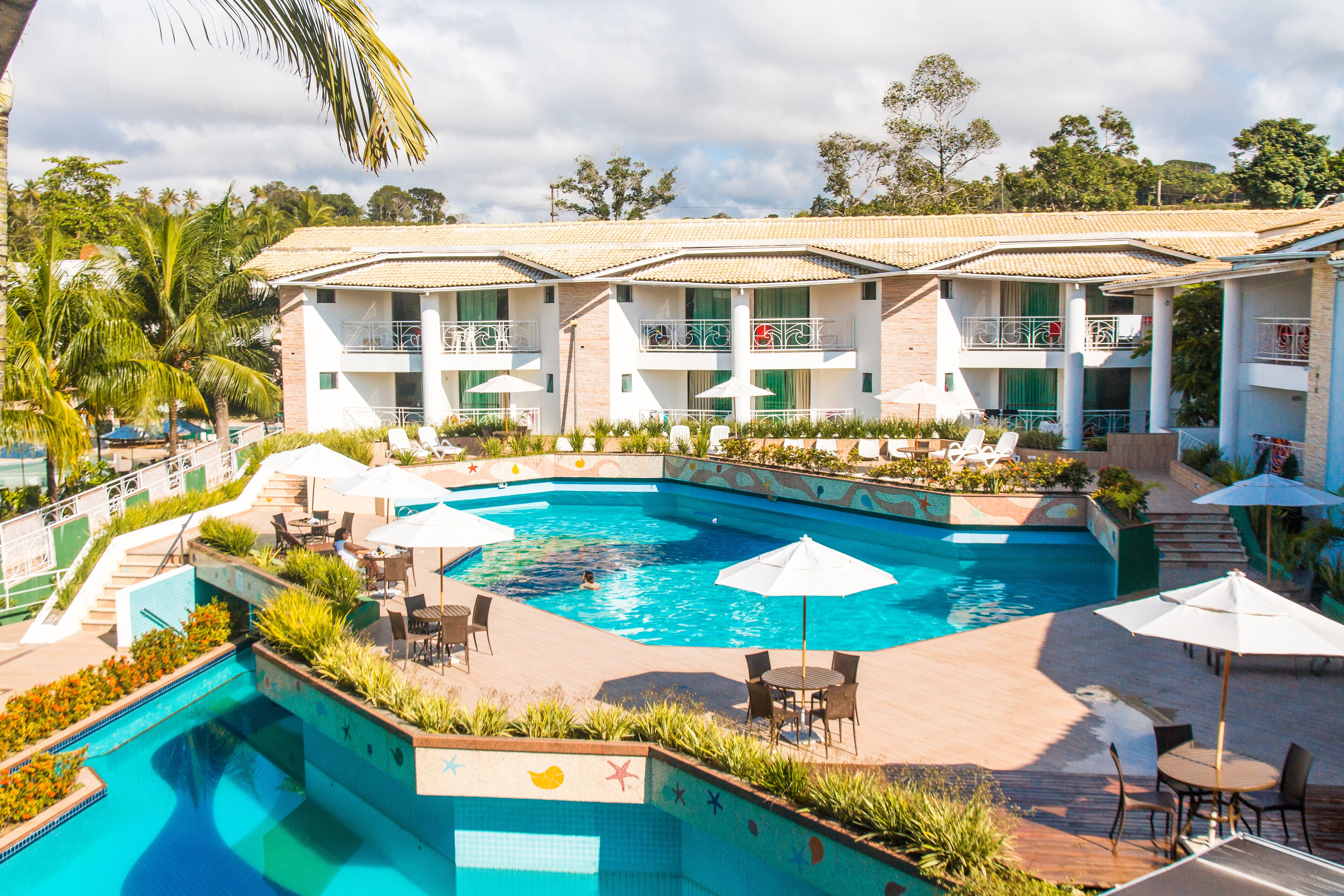 A hotel with a swimming pool, outdoor seating, and a garden area.