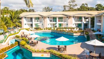 A hotel with a swimming pool, outdoor seating, and a garden area.